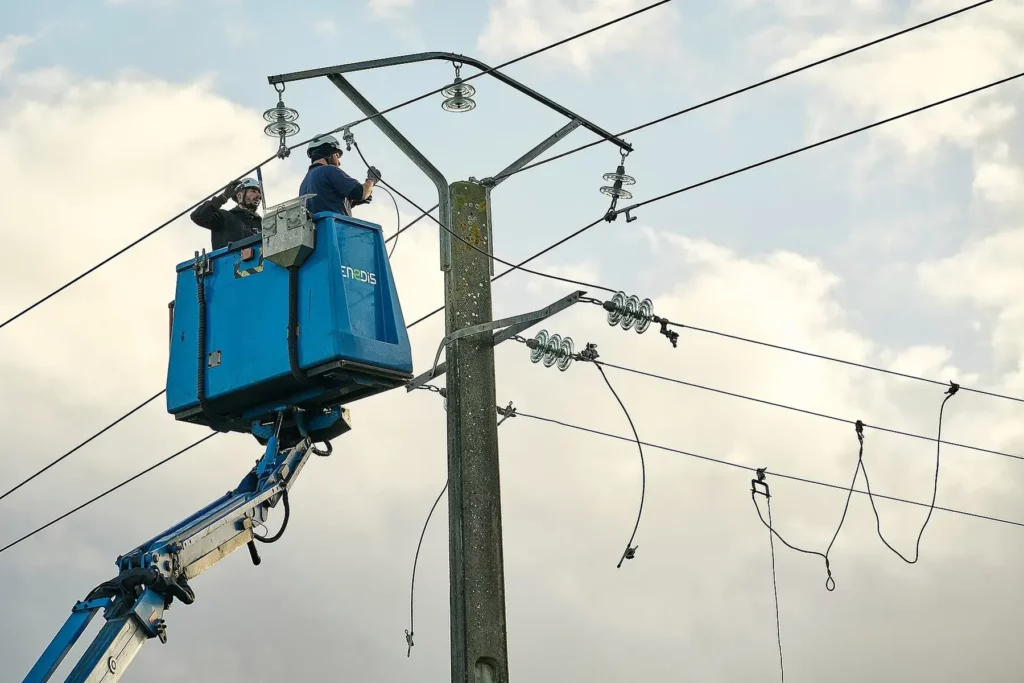 Deux techniciens Enedis intervenant sur des lignes haute tension depuis une nacelle